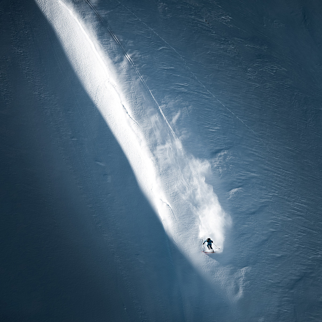 Aerial view of a rider dropping into a steep snow spine